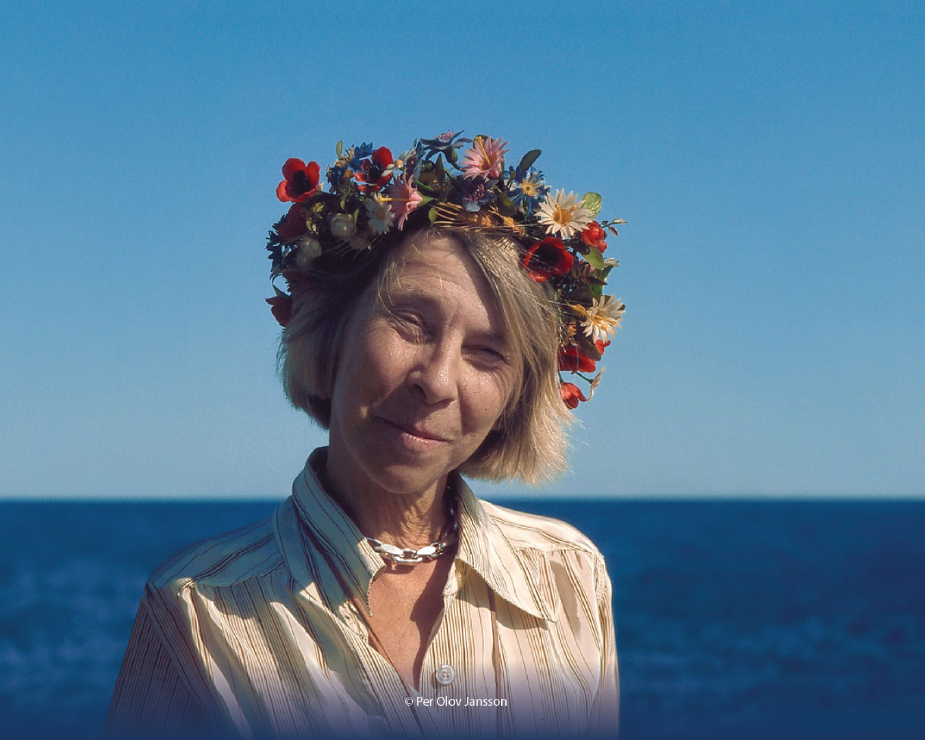 Tove Jansson wearing a flower crown by the sea